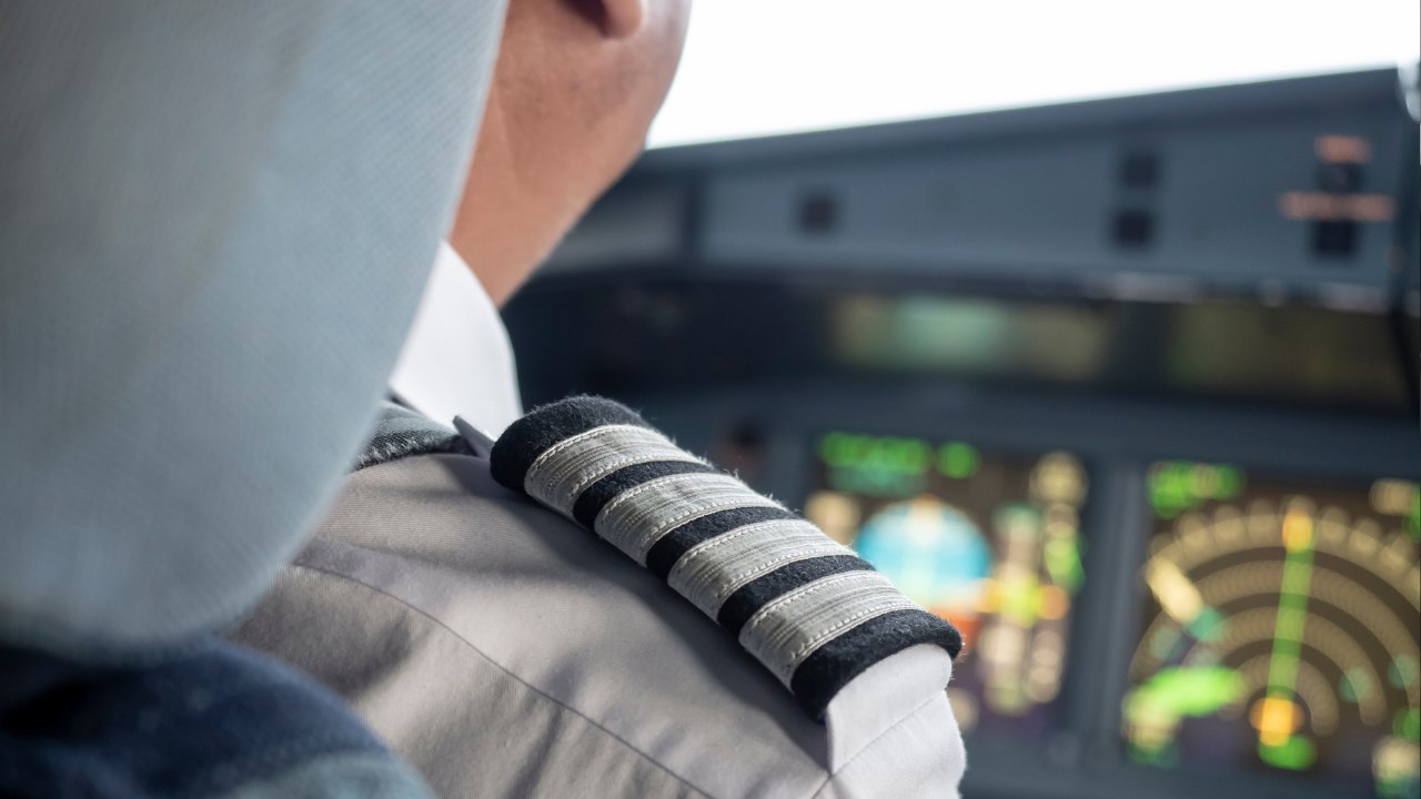 A captain's four-stripe epaulette on the flight deck, the displays lit beyond